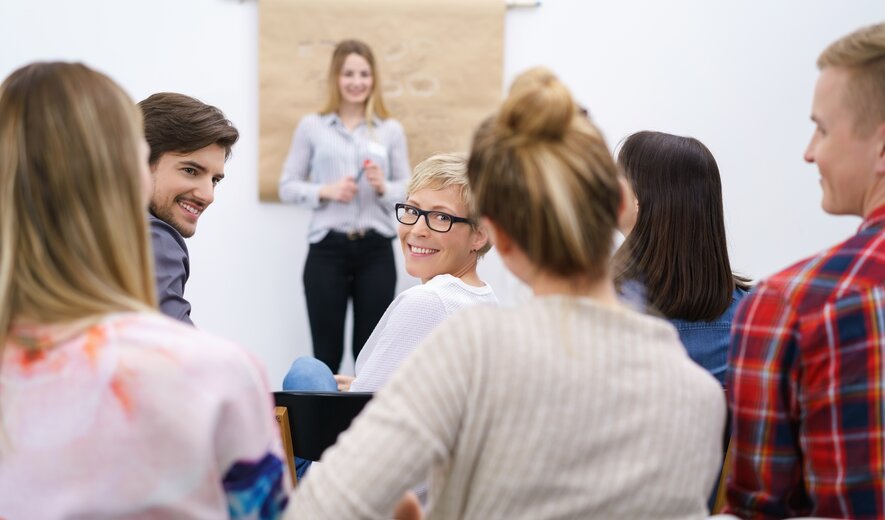 Gruppe von Teilnehmenden hört einem Vortrag in einem Seminarraum