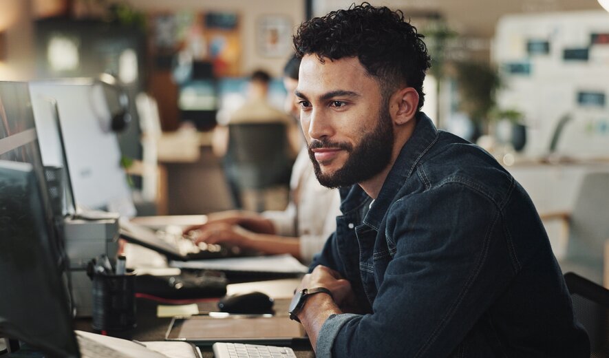 Mann arbeitet konzentriert am Computer in modernem Büro