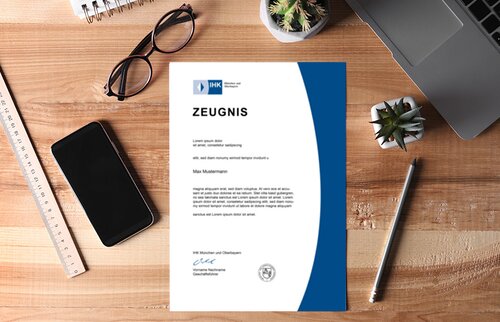 IHK-Zeugnis liegt auf Schreibtisch mit Laptop, Smartphone und Arbeitsutensilien