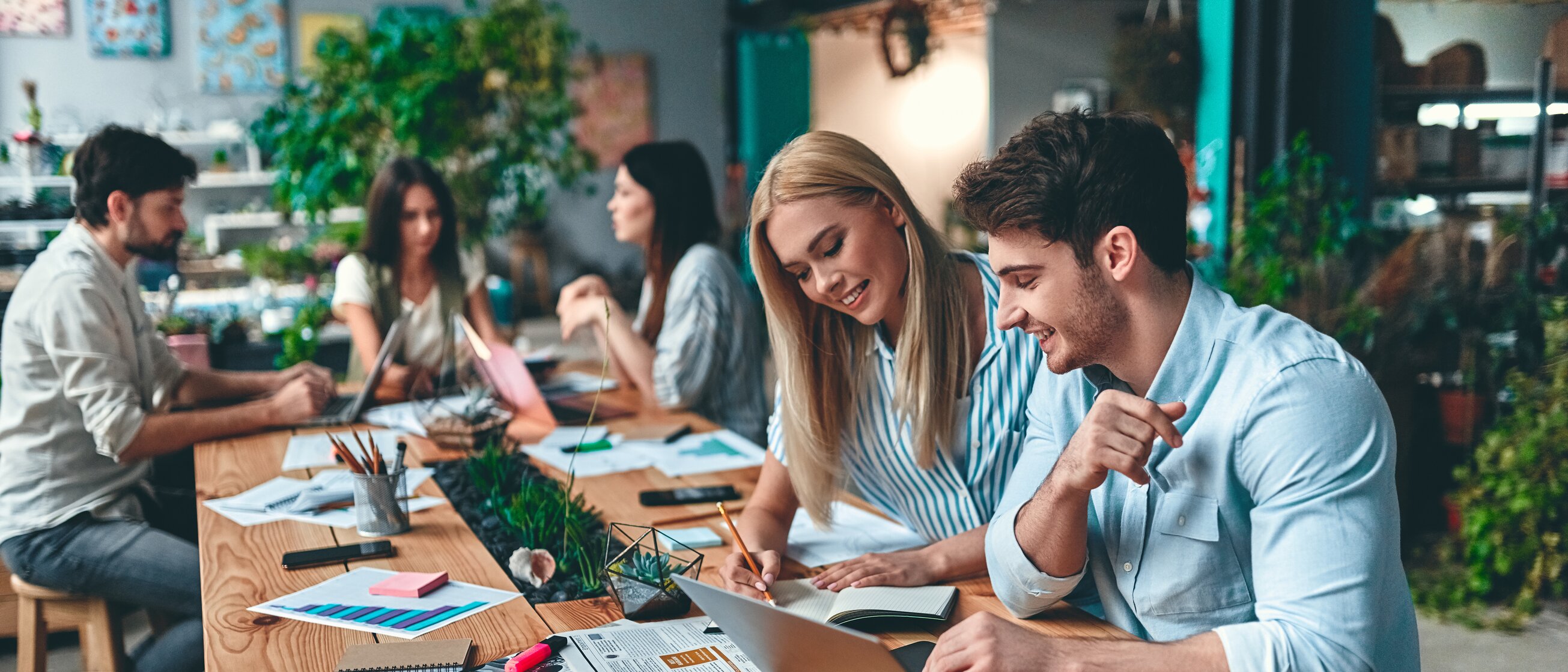 Gruppe von Teilnehmer/-innen arbeitet gemeinsam an Laptops und Unterlagen – modernes Lernen bei der IHK Akademie München mit Fokus auf Austausch, Praxis und Flexibilität in verschiedenen Lehrgangsformaten.
