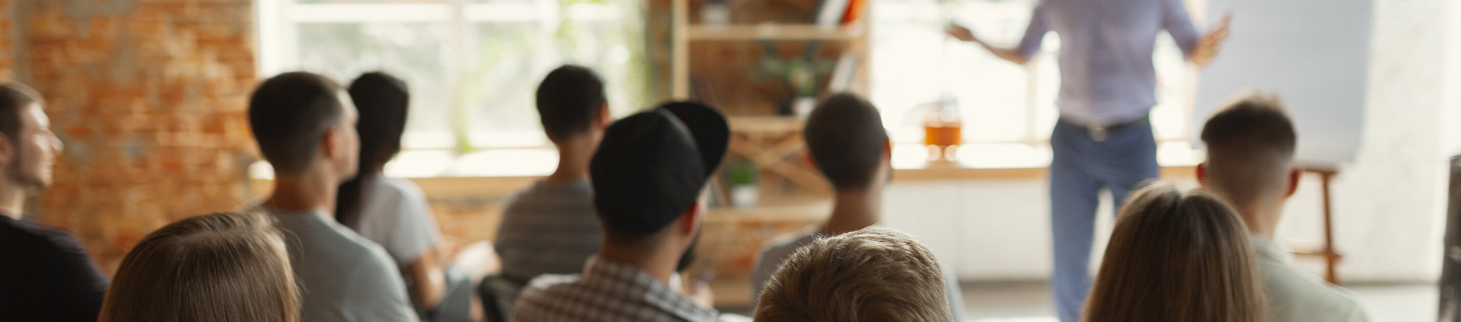 Teilnehmende sitzen im Seminarraum und hören Präsentation eines Trainers