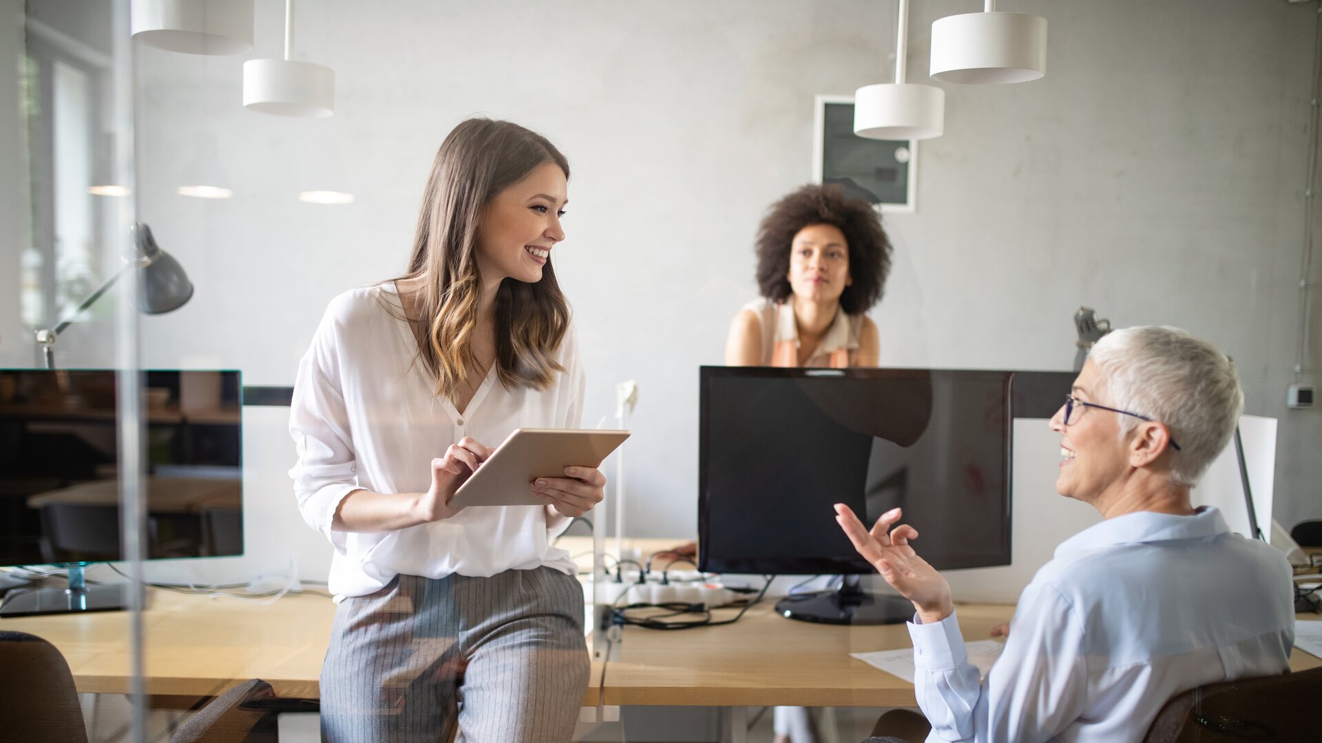 Drei Frauen im modernen Büro im Austausch über ein Projekt
