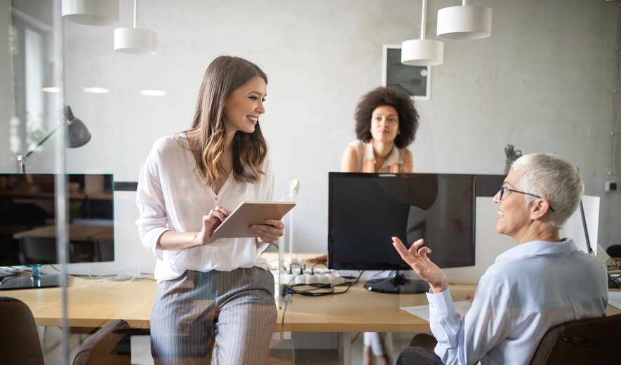 Drei Frauen im modernen Büro im Austausch über ein Projekt