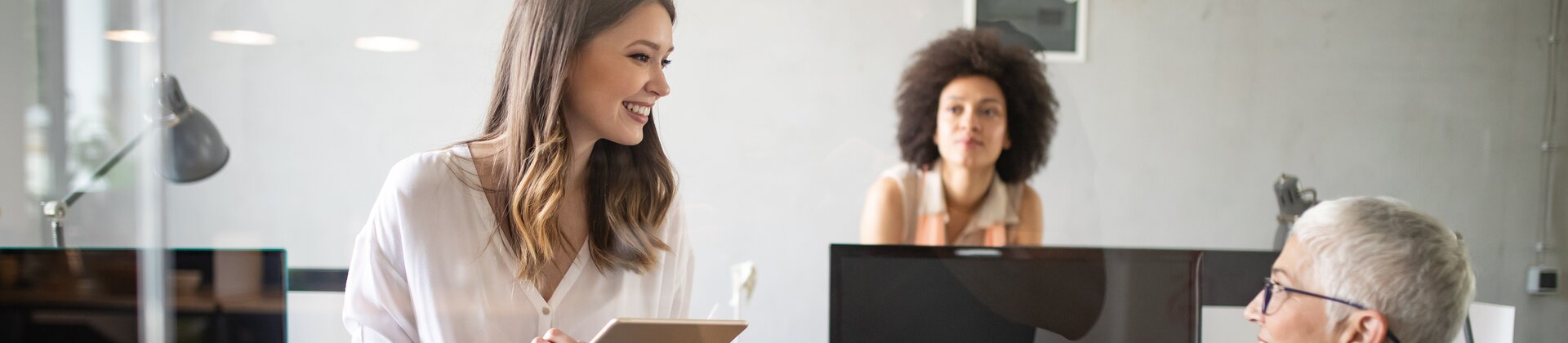 Drei Frauen im modernen Büro im Austausch über ein Projekt