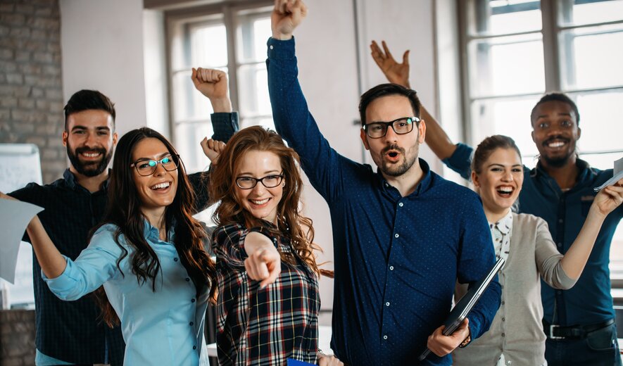 Team feiert gemeinsamen Erfolg und zeigt motiviert auf die Kamera