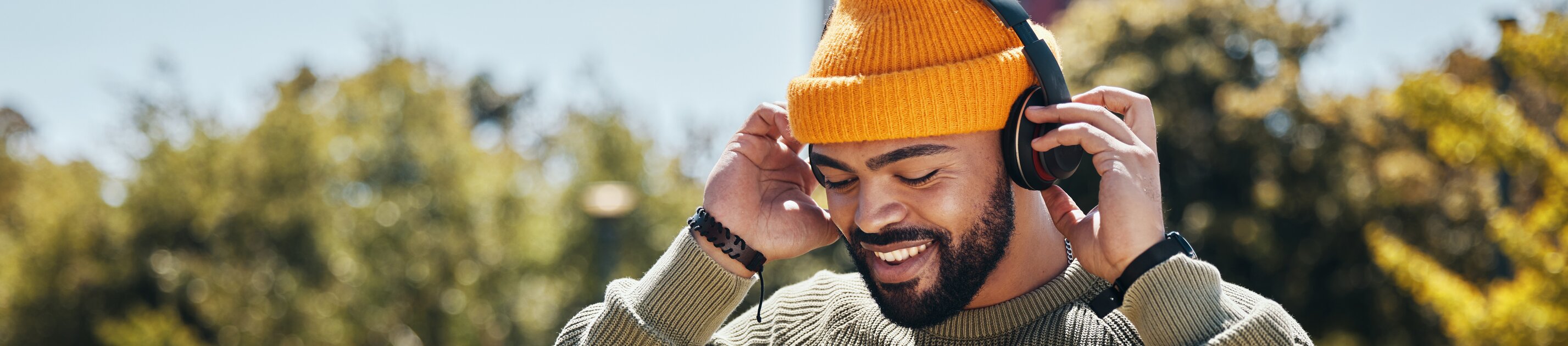 Mann hört entspannt Musik mit Kopfhörern beim Spaziergang im Park