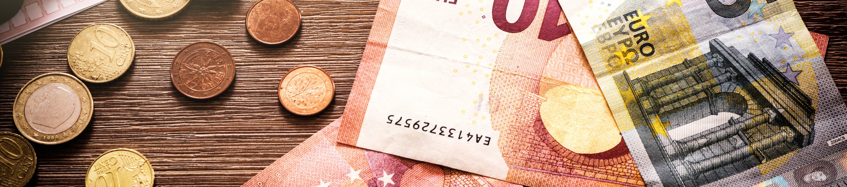 Euro-Scheine und Münzen liegen auf Tisch neben Taschenrechner als Symbol für Finanzen und Budgetplanung