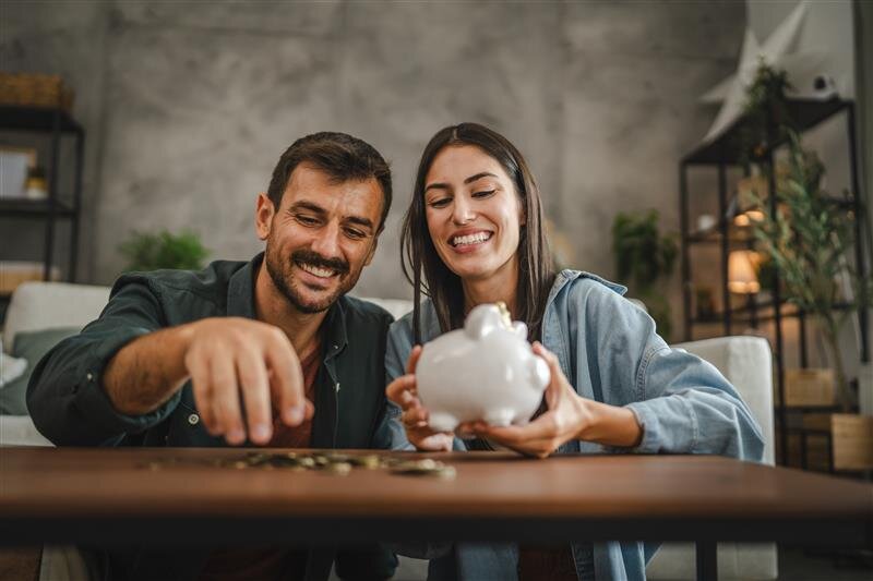 Paar zählt Münzen neben Sparschwein – Darstellung des Meisterbonus für erfolgreiche IHK-Absolventen