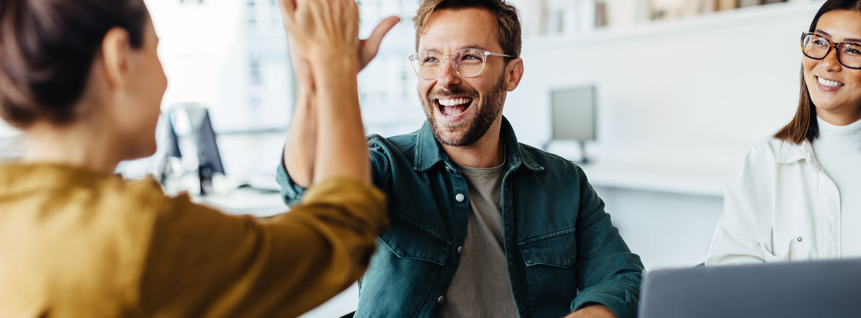 Team gibt High-Five im Büro, daneben Wertefelder mit Kompetenz, Verlässlichkeit, Ambiente.