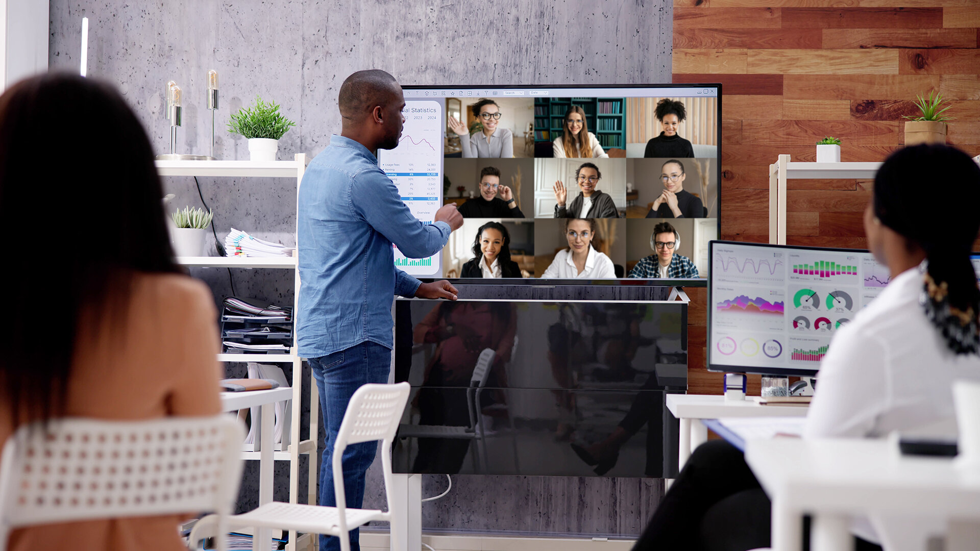 Trainer unterrichtet hybrid: Teilnehmende vor Ort und online zugeschaltet – symbolisiert modernes, digitales und flexibles Lernen bei der IHK Akademie München und Oberbayern.