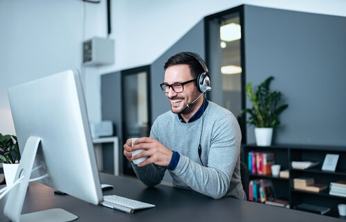 Trainer mit Headset unterrichtet online am Laptop