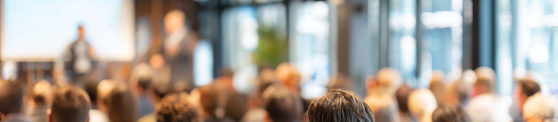 Teilnehmer/-innen einer Infoveranstaltung zu Weiterbildungen in Ingolstadt hören einem Vortrag im modernen Konferenzraum zu.