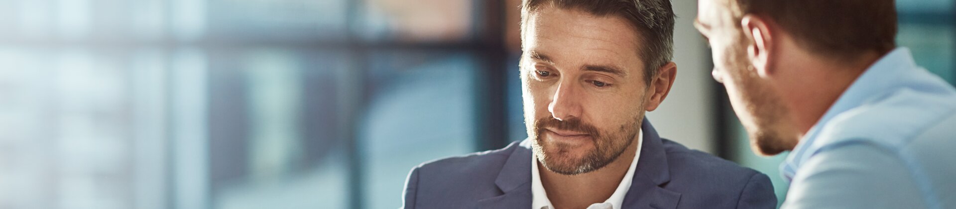 Zwei Geschäftsleute besprechen Unterlagen am Tablet – symbolisch für souveräne und selbstbewusste Preisverhandlungen.