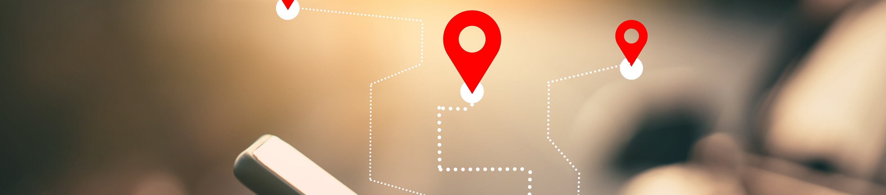 Das Bild zeigt eine Person, die ein Smartphone bedient, während darüber grafisch Navigations-Pins und eine gestrichelte Route eingeblendet sind: eine Darstellung für GPS-Navigation oder Standortverfolgung.