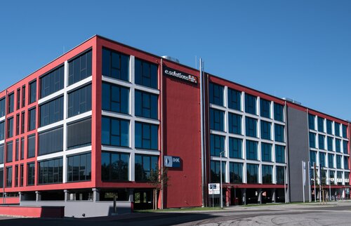 moderner ihk akademie standort mit rot-grauem bürogebäude und großer glasfassade