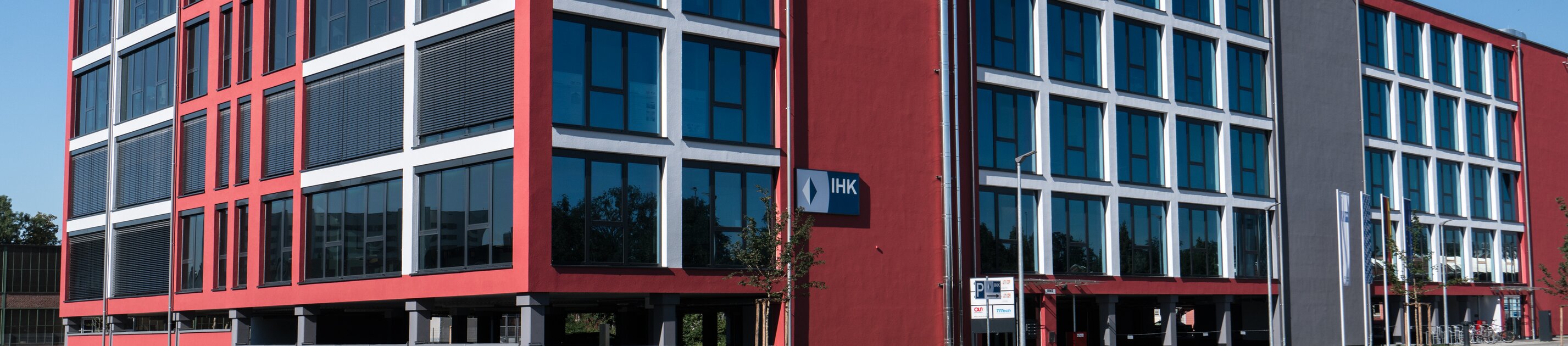 moderner ihk akademie standort mit rot-grauem bürogebäude und großer glasfassade
