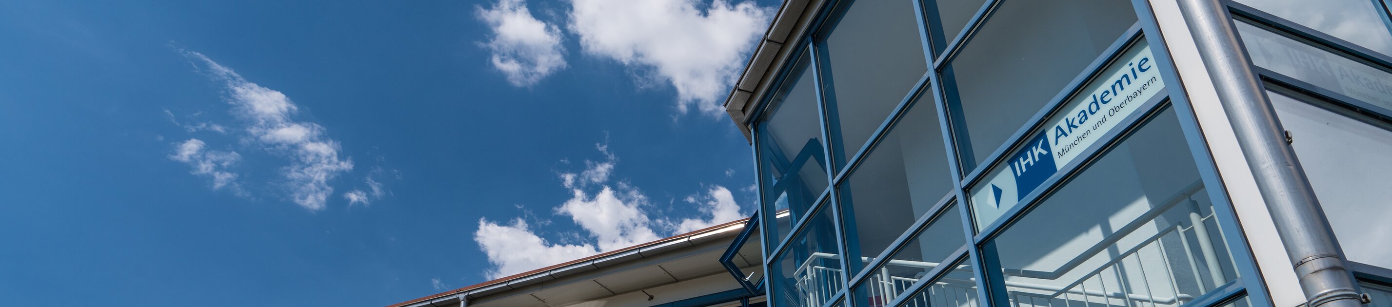 moderner ihk akademie standort  mit glasfassade und blau-weißer fassade unter blauem himmel