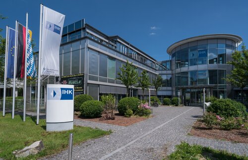 ihk akademie gebäude mit glasfassade eingangsbereich und fahnen bei sonnigem wetter
