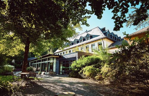 IHK Akademie Westerham Außenbereich mit historischem Hauptgebäude, lichtdurchflutetem Seminartrakt und idyllischem Garten mit Sitzplätzen im Grünen