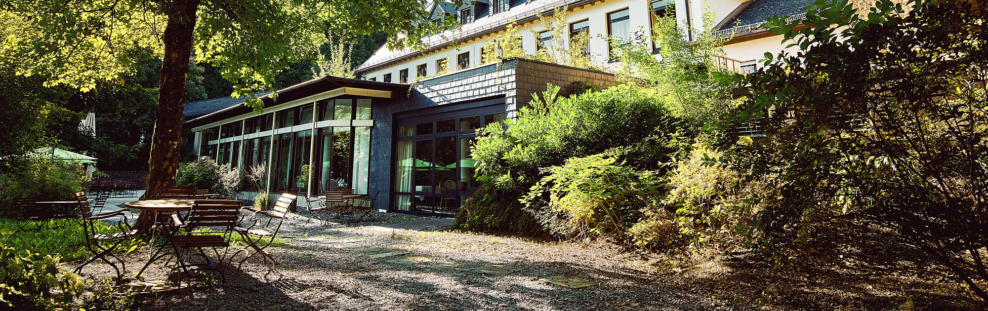 IHK Akademie Westerham Außenbereich mit historischem Hauptgebäude, lichtdurchflutetem Seminartrakt und idyllischem Garten mit Sitzplätzen im Grünen