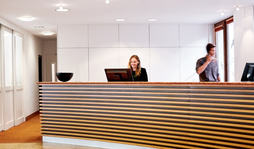 Moderne Rezeption in der IHK Akademie Westerham mit freundlicher Mitarbeiterin am Empfang und hellem, einladendem Foyer