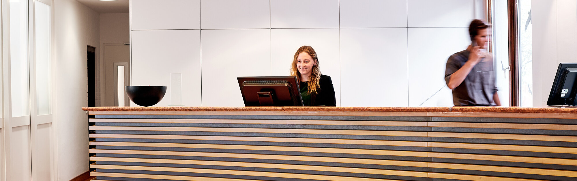 Moderne Rezeption in der IHK Akademie Westerham mit freundlicher Mitarbeiterin am Empfang und hellem, einladendem Foyer
