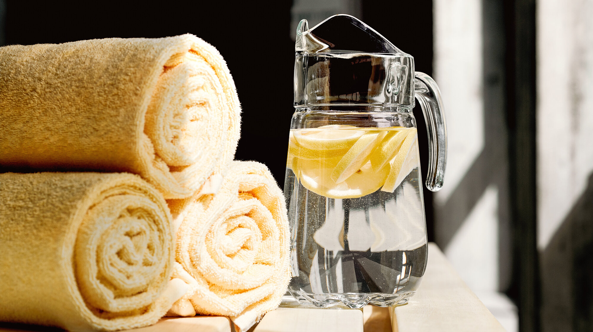 Gerollte gelbe Handtücher und eine Glaskaraffe mit Zitronenwasser im Spa-Bereich der Akademie Westerham