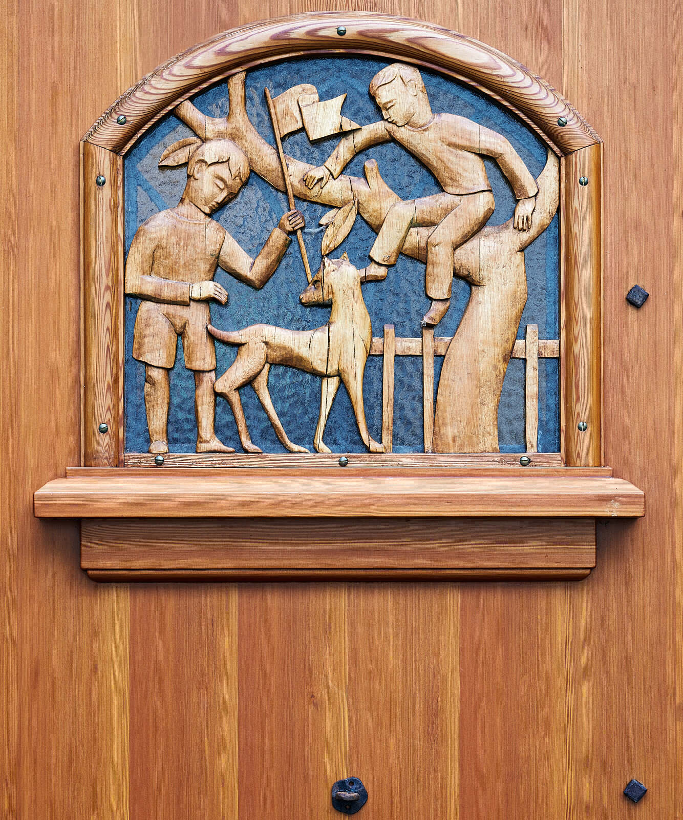 Holzrelief an einer Tür in der IHK Akademie Westerham mit handgeschnitzter Darstellung spielender Kinder, ein historisches Detail aus der ursprünglichen Bauzeit des Hauses.