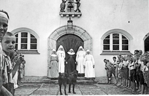 Historische Aufnahme von 1927: Ordensschwestern der Mallersdorfer Franziskanerinnen begrüßen die ersten Kinder vor dem Eingang des Kinderkurheims Westerham, flankiert von Kindern in Reihen