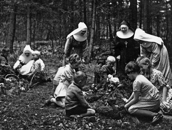 Historische Schwarz-Weiß-Aufnahme von Kindern und Ordensschwestern bei der Gartenarbeit im Kinderkurheim Westerham