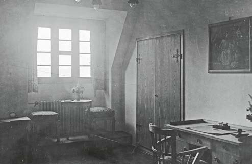 Schwarz-Weiß-Aufnahme eines kindgerecht eingerichteten Zimmers im Kinderkurheim Westerham mit Tisch, Stühlen, Fenster und einfacher Einrichtung der 1920er Jahre