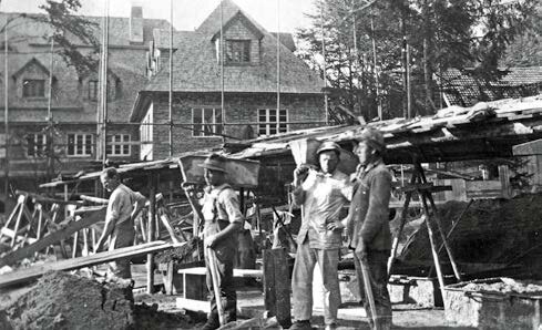 Schwarz-Weiß-Fotografie vom Bau des Kinderkurheims Westerham im Jahr 1926 – Bauarbeiter beim Errichten der Gebäude mit Holzgerüsten und Baumaterialien im Vordergrund