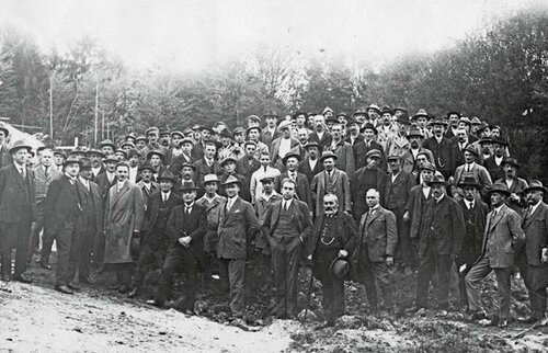 Historische Gruppenaufnahme beim Richtfest des Kinderkurheims Westerham um 1926 – zahlreiche Männer in Anzügen und Hüten, versammelt vor dem Neubau, umgeben von Bäumen