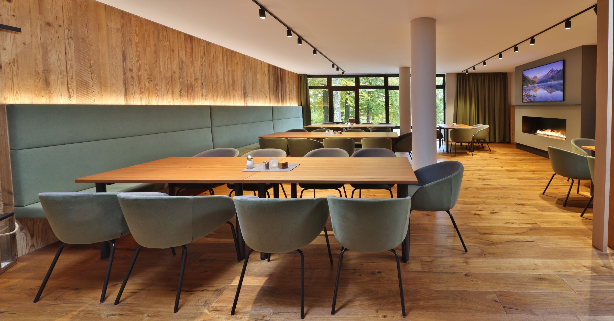 Moderner Speisebereich der Akademie Westerham mit Holzdesign, Kamin und großen Fenstern mit Blick ins Grüne