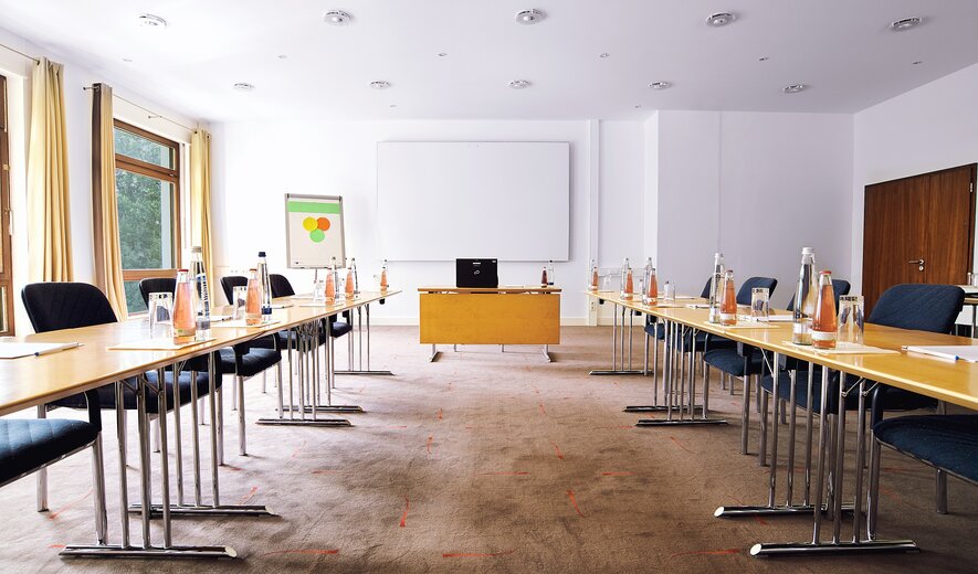 Ein klar strukturierter Seminarraum, der mit viel Tageslicht und professioneller Ausstattung ideale Bedingungen für produktives Arbeiten schafft.