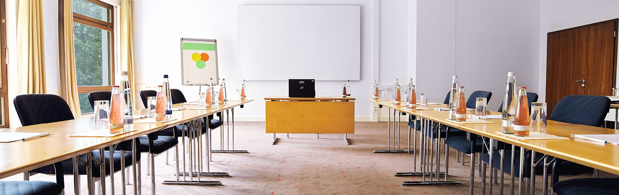 Ein klar strukturierter Seminarraum, der mit viel Tageslicht und professioneller Ausstattung ideale Bedingungen für produktives Arbeiten schafft.