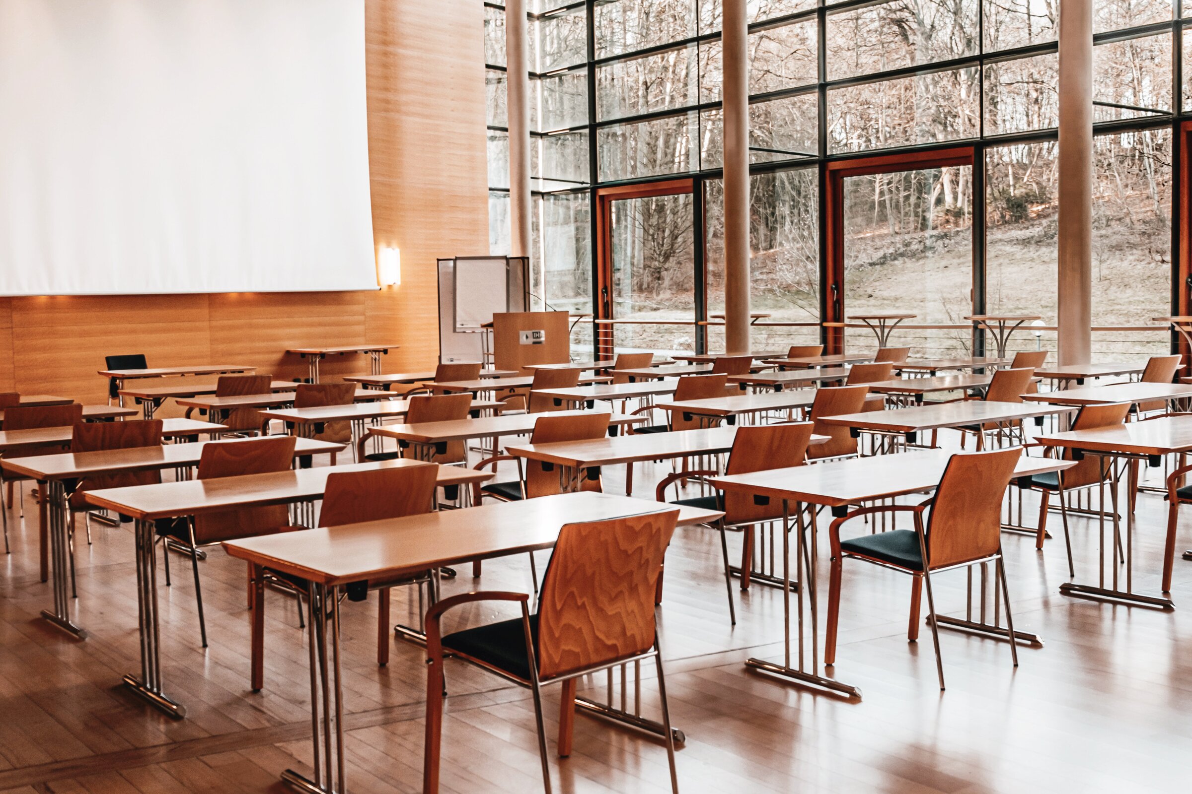 Großer Tagungssaal in der Akademie Westerham mit moderner Bestuhlung, Holzinterieur und bodentiefen Fenstern mit Blick in die Natur