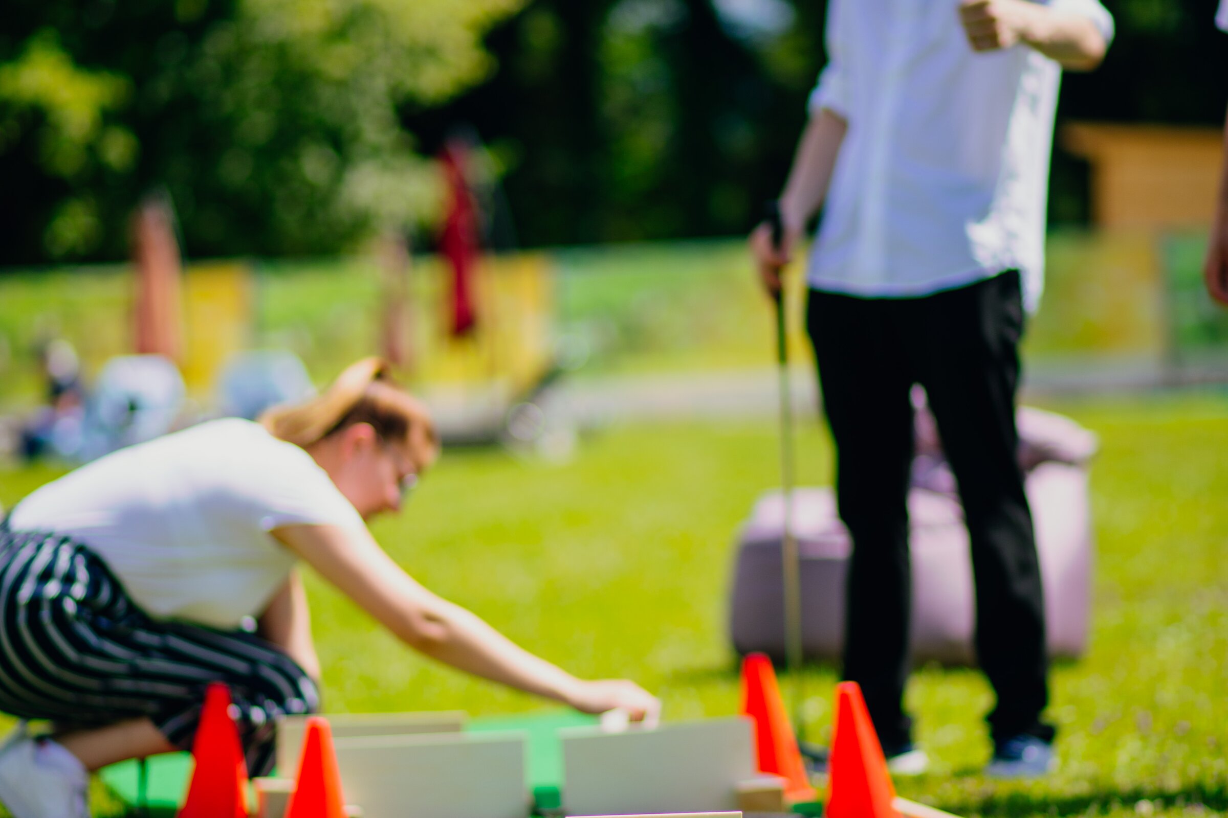 Zwei Teilnehmende bauen eine Minigolfbahn mit Hindernissen im Freien – Selfmade-Minigolf-Teamevent in Westerham