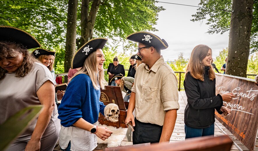 teilnehmende tragen piratenhüte und lösen gemeinsam outdoor-aufgaben bei einem piraten-teamspiel