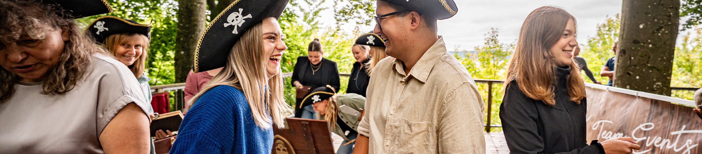 teilnehmende tragen piratenhüte und lösen gemeinsam outdoor-aufgaben bei einem piraten-teamspiel