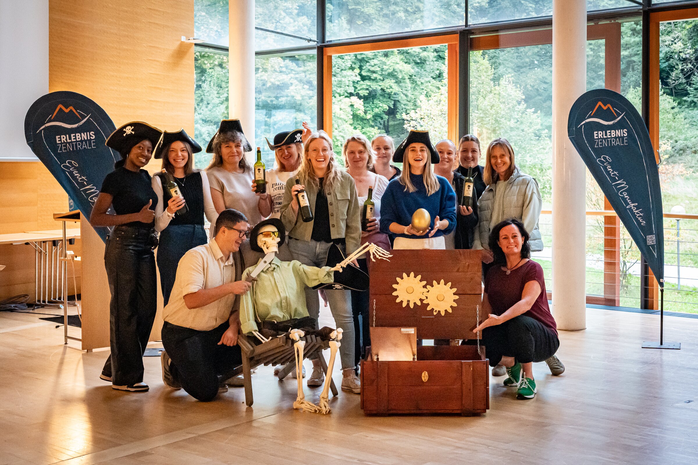 Gruppe von Teilnehmenden mit Piratenhüten posiert gemeinsam mit einer Schatztruhe und Requisiten