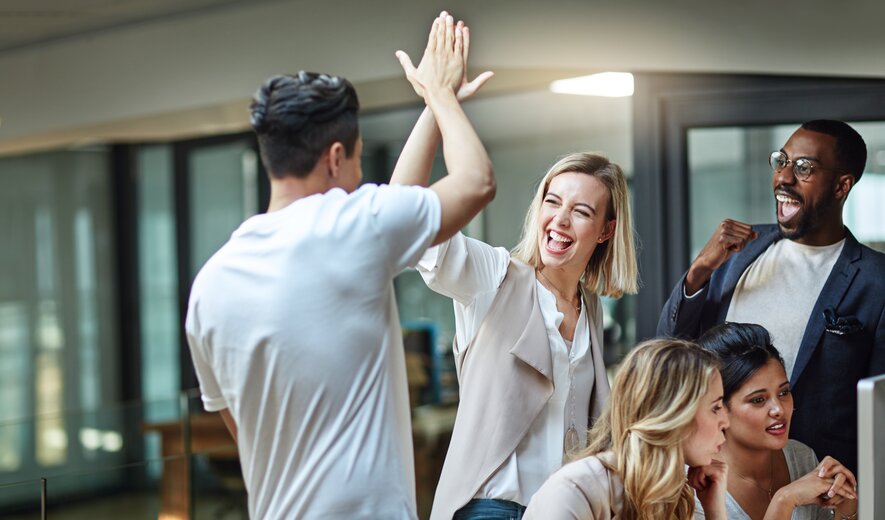 team feiert einen erfolg im büro mit high-five und begeisterten reaktionen