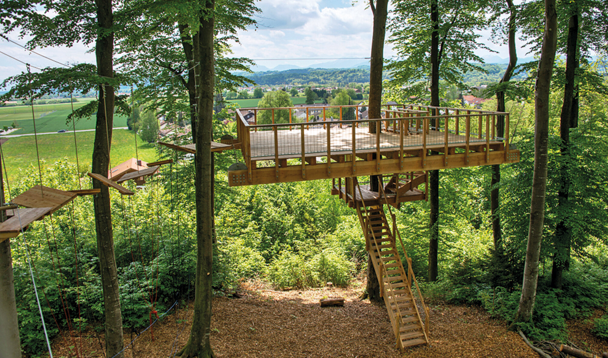 Holzplattform der IHK Akademie Westerham zwischen Bäumen über dem Akademiewald – inspirierender Lernort mit Ausblick auf die umliegende Landschaft