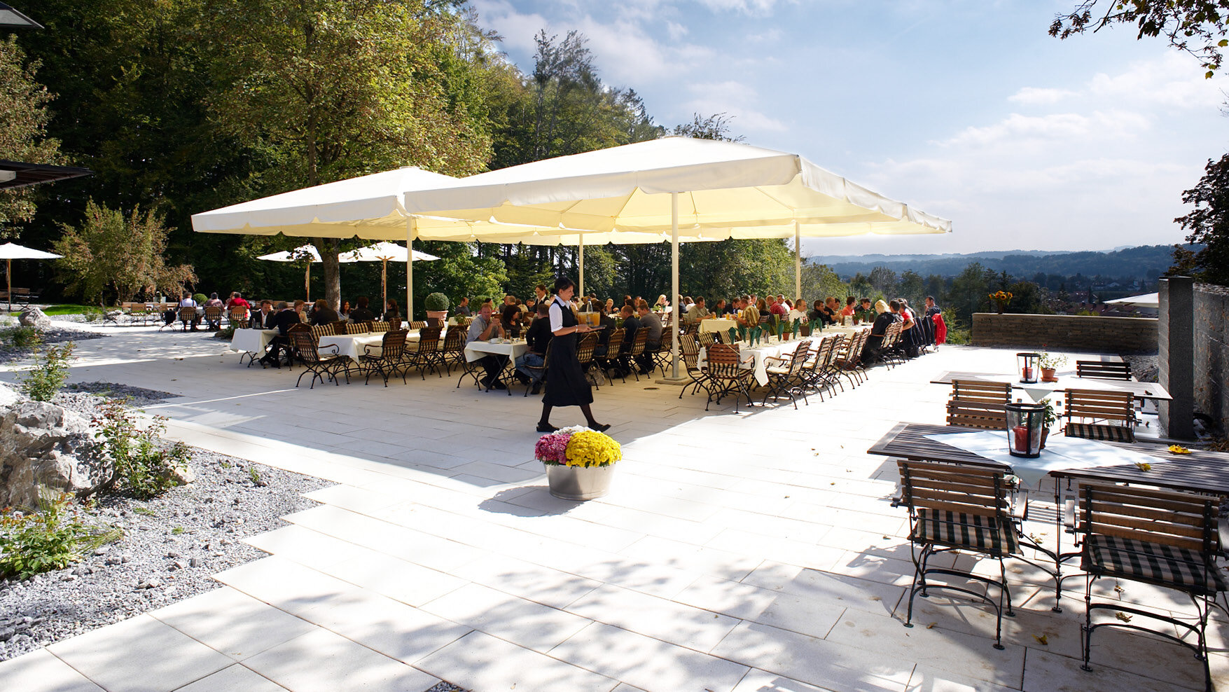 Panoramaterrasse der Akademie in Westerham mit Gästen unter großen Sonnenschirmen bei schönem Wetter