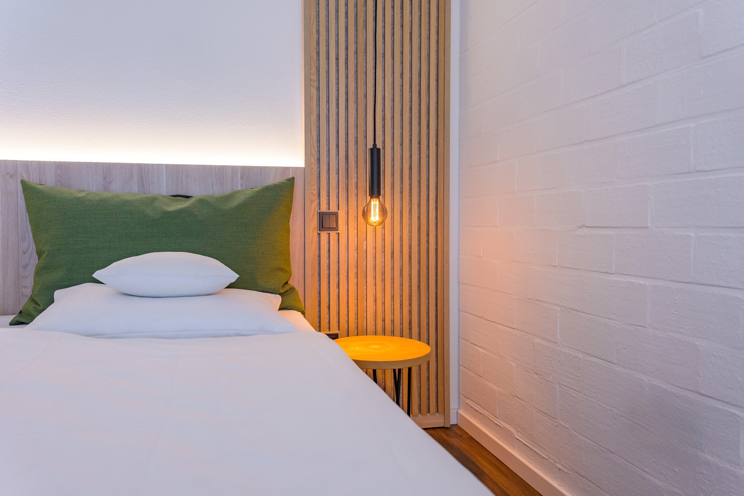 Modernes Einzelzimmer der Akademie Westerham mit gemütlichem Bett, warmem Licht und grünem Kopfkissen