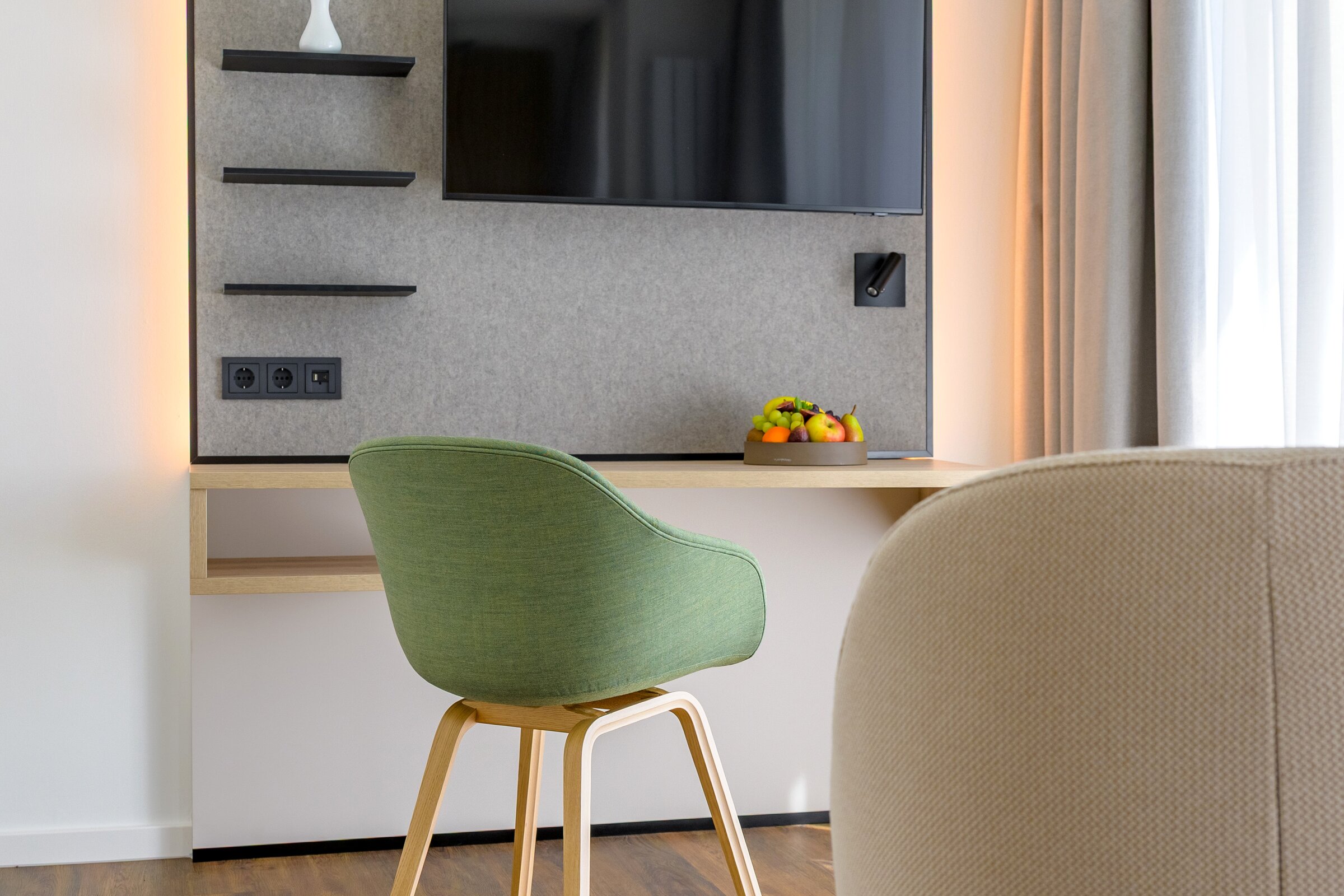 Moderner Arbeitsbereich im Gästezimmer der Akademie Westerham mit grünem Stuhl, Holzschreibtisch und Fernseher