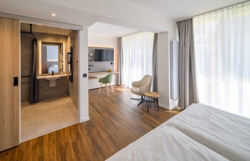 Helles Doppelzimmer der Akademie Westerham mit Doppelbett, modernem Bad, Schreibtisch und Balkon mit Waldblick