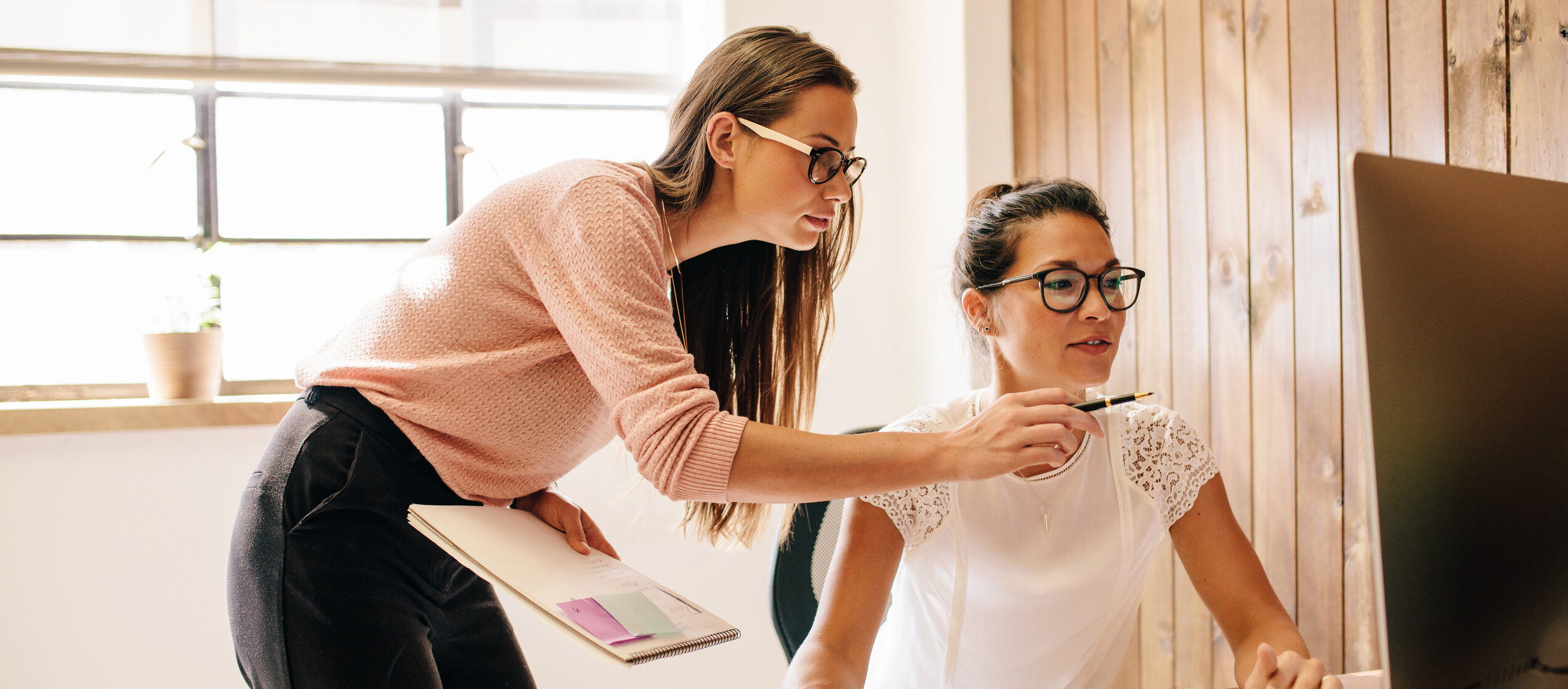 Weiterbildung im Bereich Projektkoordination & Management: Zwei Frauen arbeiten gemeinsam am Computer und besprechen Inhalte – Symbol für Teamarbeit und berufliche Weiterbildung.