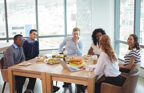 Gruppe von Fachleuten sitzt am Tisch im modernen Büro und unterhält sich – Symbol für gemeinsames Lernen beim Ausbilderfrühstück Ingolstadt.