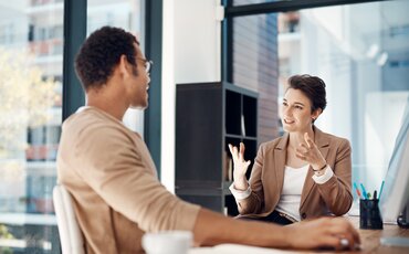 Zwei Personen im Gespräch im Büro – Symbol für erfolgreiche Kommunikation und Zusammenarbeit.